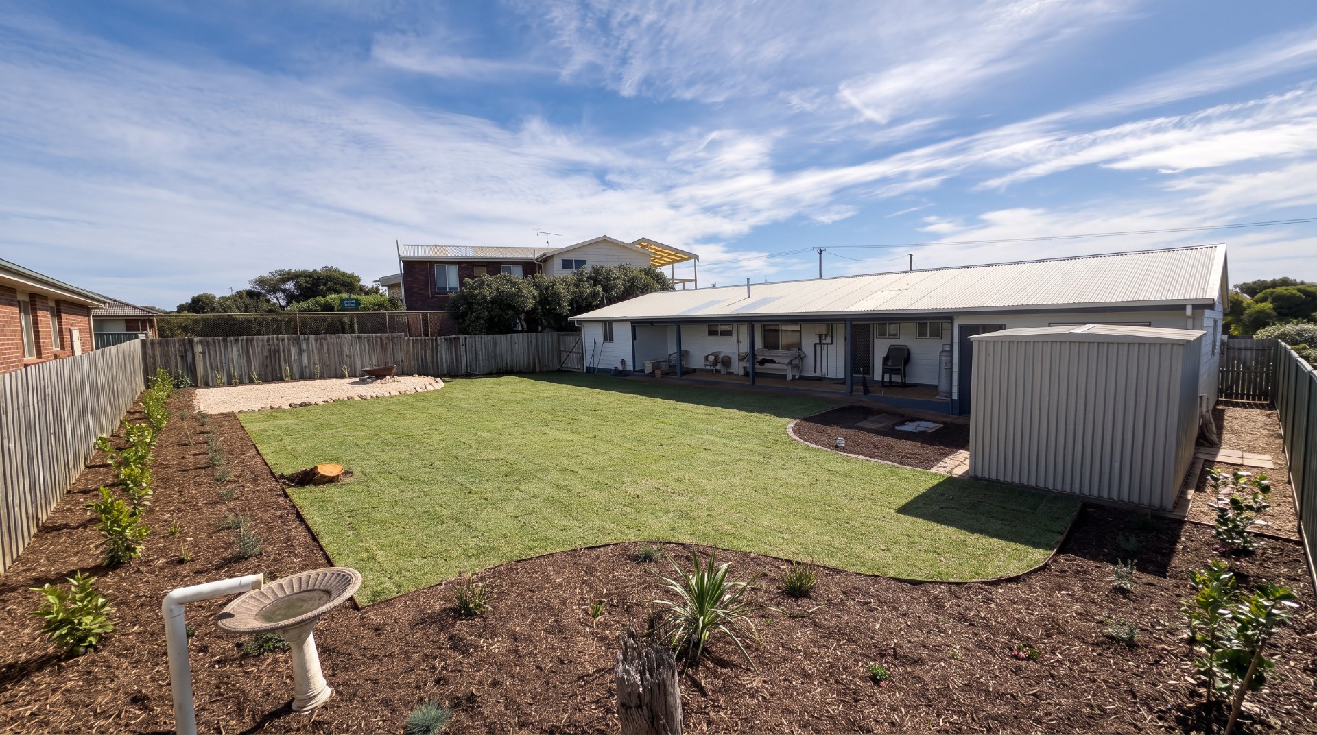 Backyard with new turf, curved steel edging and fresh mulched garden beds
